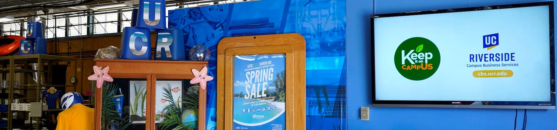 Interior of ScotSurplus with a TV screen saying "Campus Business Services: Keep It On Campus."