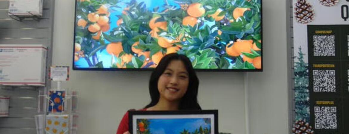 The 2026-27 R'Card Winner, Valerie Cheng, holds up her design in HSS.