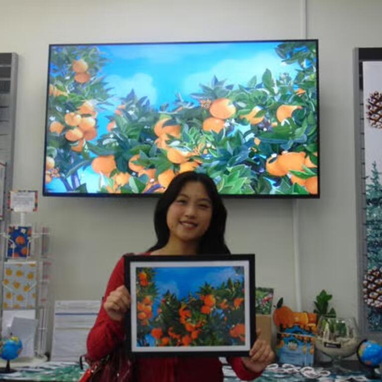 The 2026-27 R'Card Winner, Valerie Cheng, holds up her design in HSS.