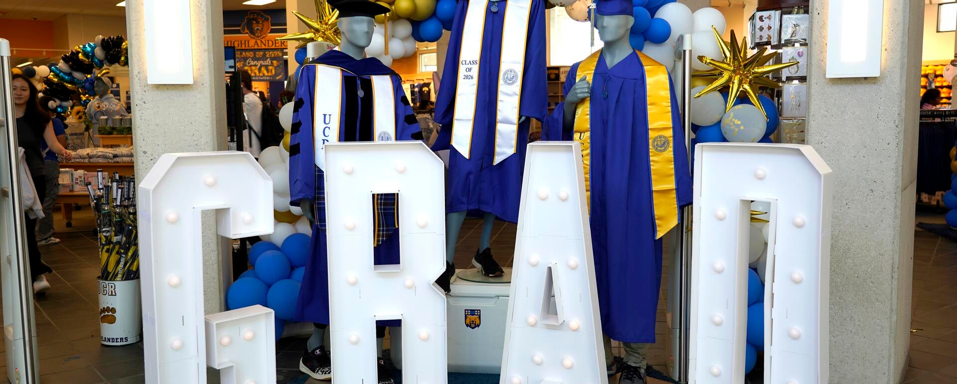 Light-up letters that spell out GRAD with blue graduation robes.