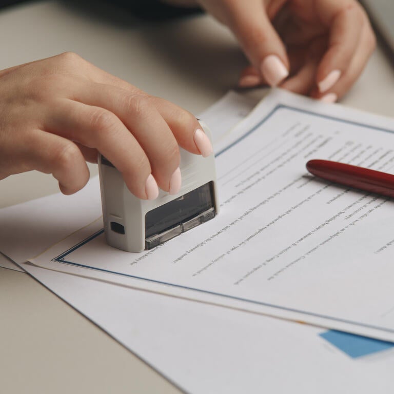 A person notarizes a document by stamping it.